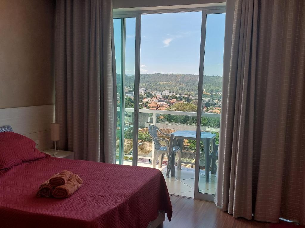 1 dormitorio con cama y vistas a un balcón en Apto ótima localização, self check-in, wi-fi, varanda e vista linda - 401, en Lagoa Santa