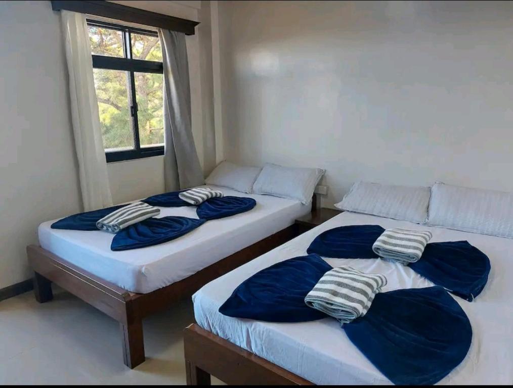 two twin beds in a room with a window at Haven Haus with Mountain View in Baguio