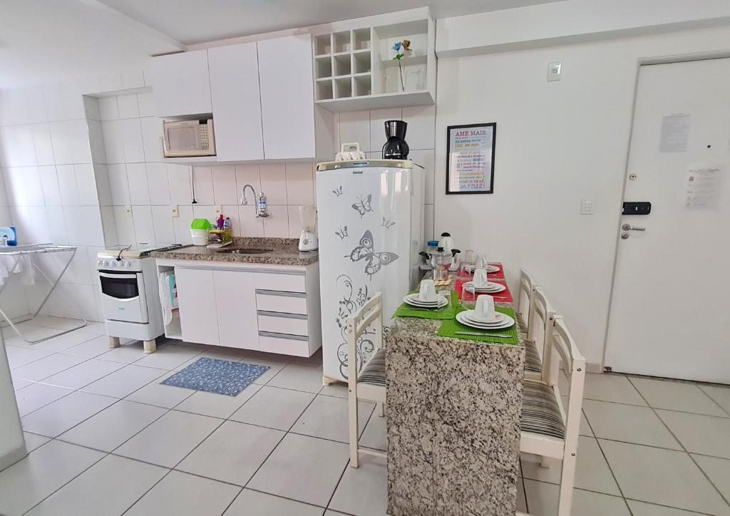 una cocina con armarios blancos y nevera. en Apartamento Monte Paradiso en Maceió