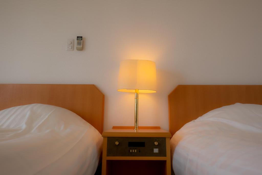 a bedroom with two beds and a lamp on a night stand at Kerama Blue Resort in Zamami