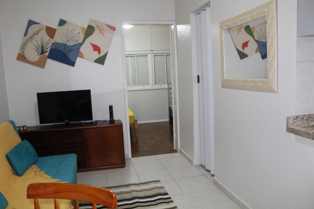 een woonkamer met een televisie en een stoel bij Apartamento à Beira-Mar e Centro Tramandaí Frente calçadão in Tramandaí