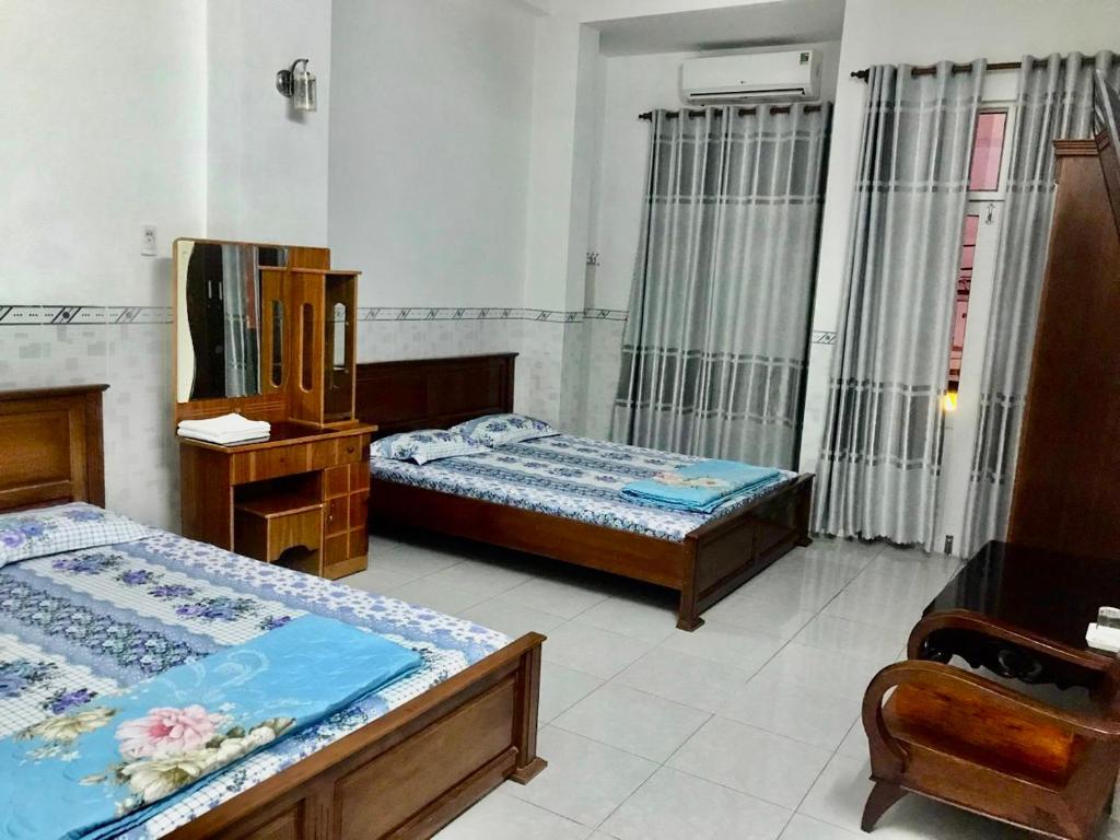 a bedroom with two beds and a dresser and a mirror at Nhà Nghỉ Hải Đăng in Quy Nhon