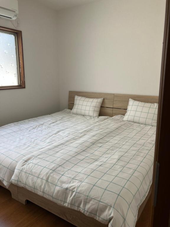 ein Bett mit zwei Kissen darauf in einem Schlafzimmer in der Unterkunft りんくう館笠松 関西空港 in Sano
