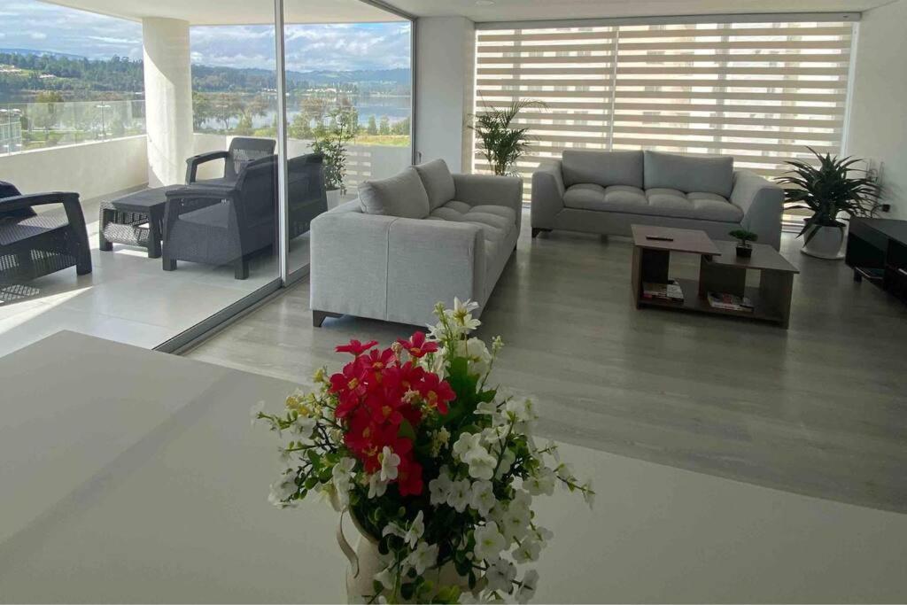 una sala de estar con sofás y un jarrón de flores en Apartamento con vista al lago., en Paipa