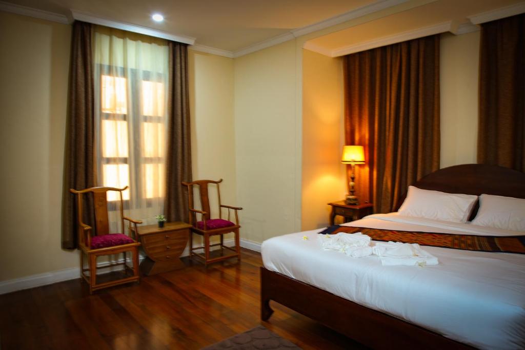 a hotel room with a bed and two chairs at Le Luxe Boutique Hotel in Ban Nongdouang