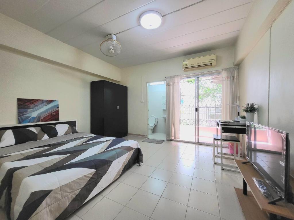 a bedroom with a bed and a desk and a window at My Space 77 in Ban Khlong Khwang Klang