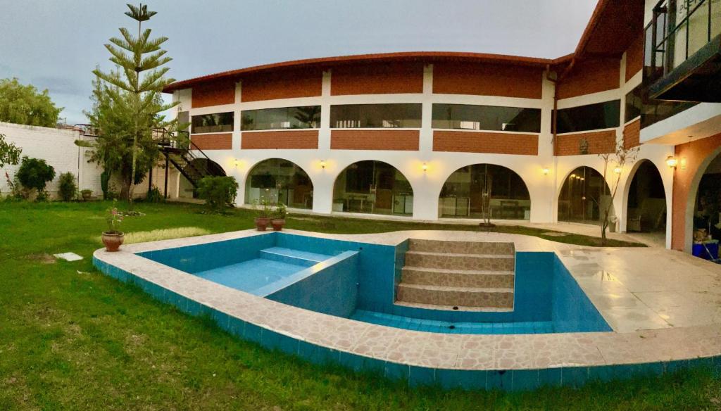 een groot gebouw met een blauw zwembad ervoor bij Alojamiento Baños del Inca in Los Baños del Inca