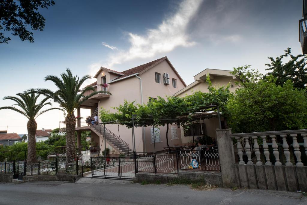 a house with a fence and palm trees at Apartments Pavićević in Tivat