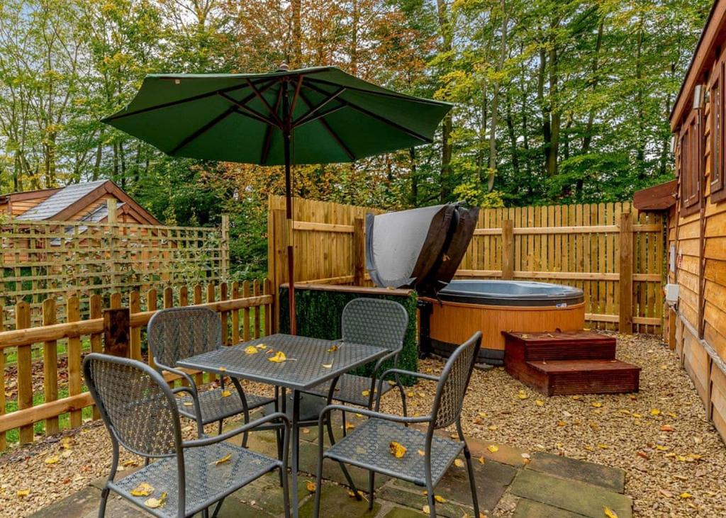 a patio with a table and chairs and an umbrella at Mallory Meadows in Kirkby Mallory