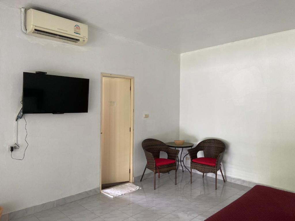 a room with a table and chairs and a television on a wall at The Sandy House Khaolak in Khao Lak