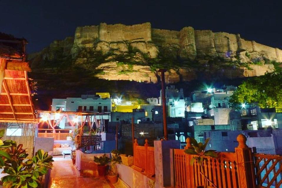 vista di una città di notte con una montagna di Pushp Guest House a Jodhpur