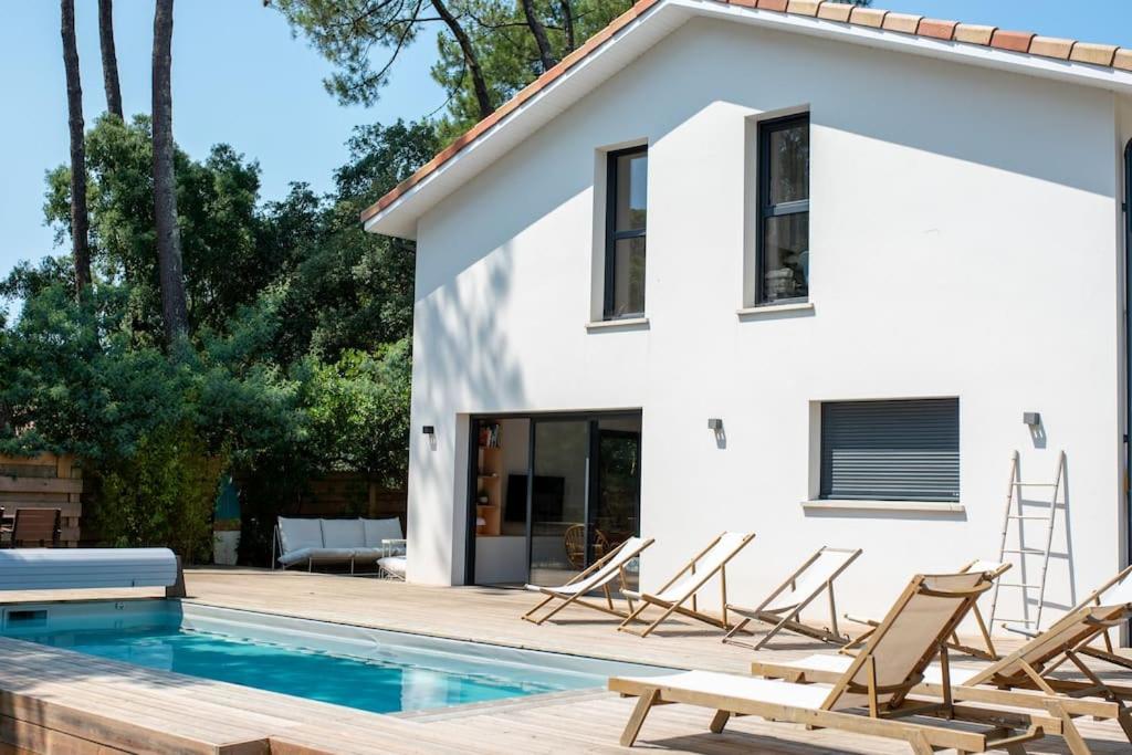Biały dom z basenem i krzesłami w obiekcie Superbe villa 5* avec piscine chauffée w mieście Labenne