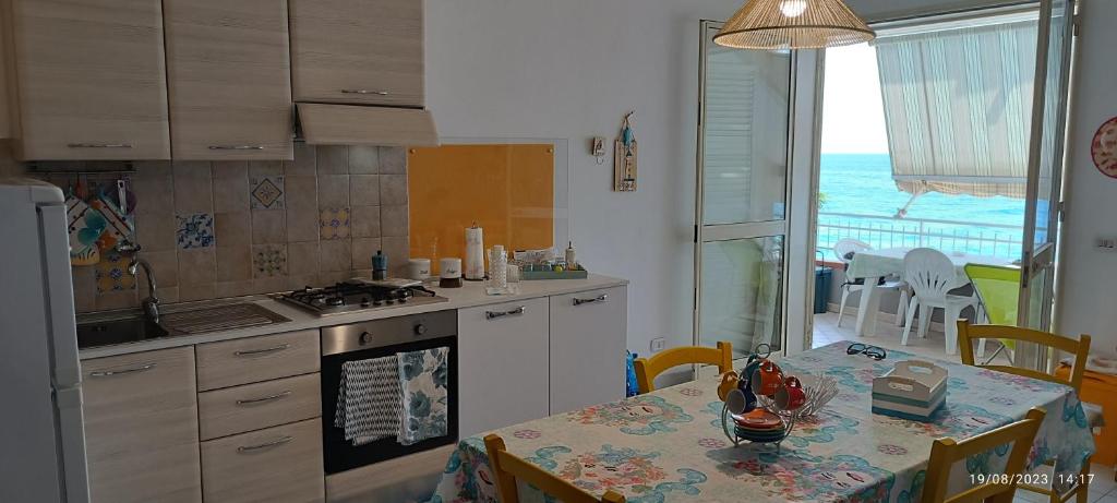a kitchen with a table and a dining room with a view at Casa fronte mare in Roccalumera