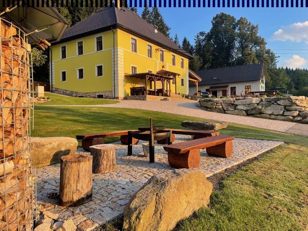 a yellow building with a picnic table and some logs at Apartmány HÁJOVNA Lipno in Loučovice