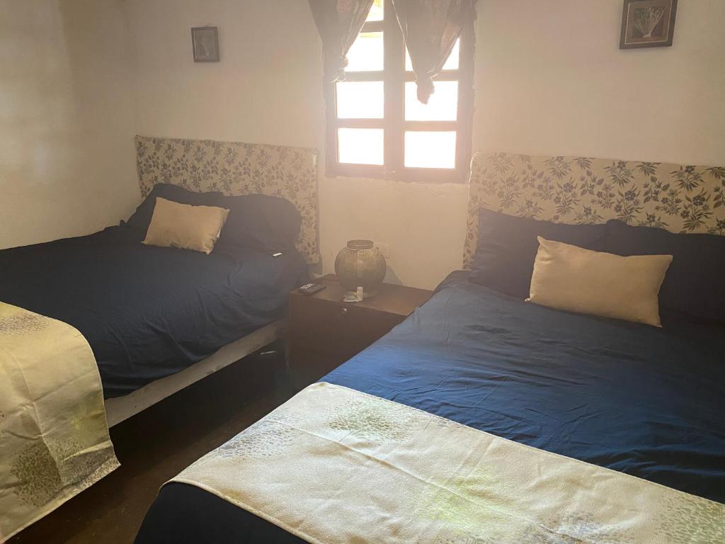 a bedroom with two beds and a window at Casa en el corazón de San Antonio de las Alazanas in San Antonio de las Alzanas