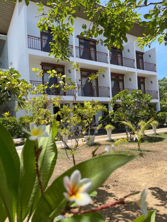 a white building with trees in front of it at Amanda Beach Resort in Pasikuda