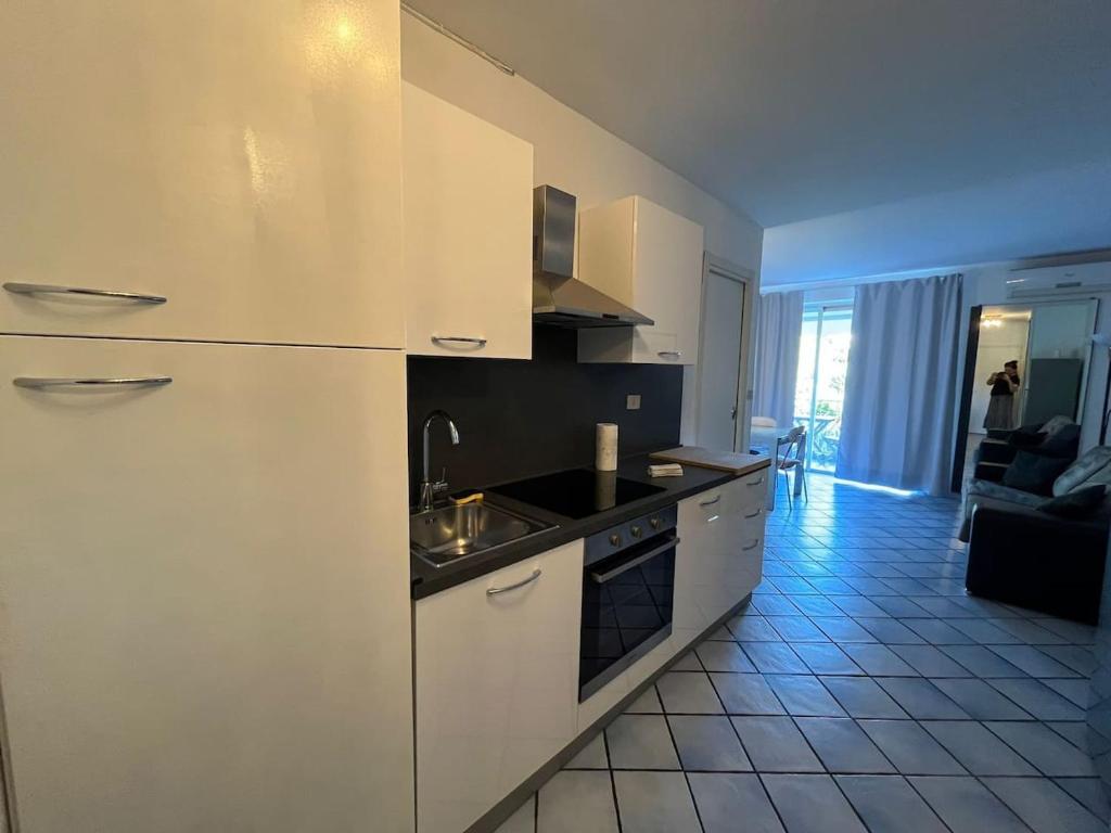 Il comprend un salon et une cuisine équipée d'appareils électroménagers blancs. dans l'établissement Dragonniere, Superbe 2P vue parc et piscine, près de Monaco, à Roquebrune-Cap-Martin