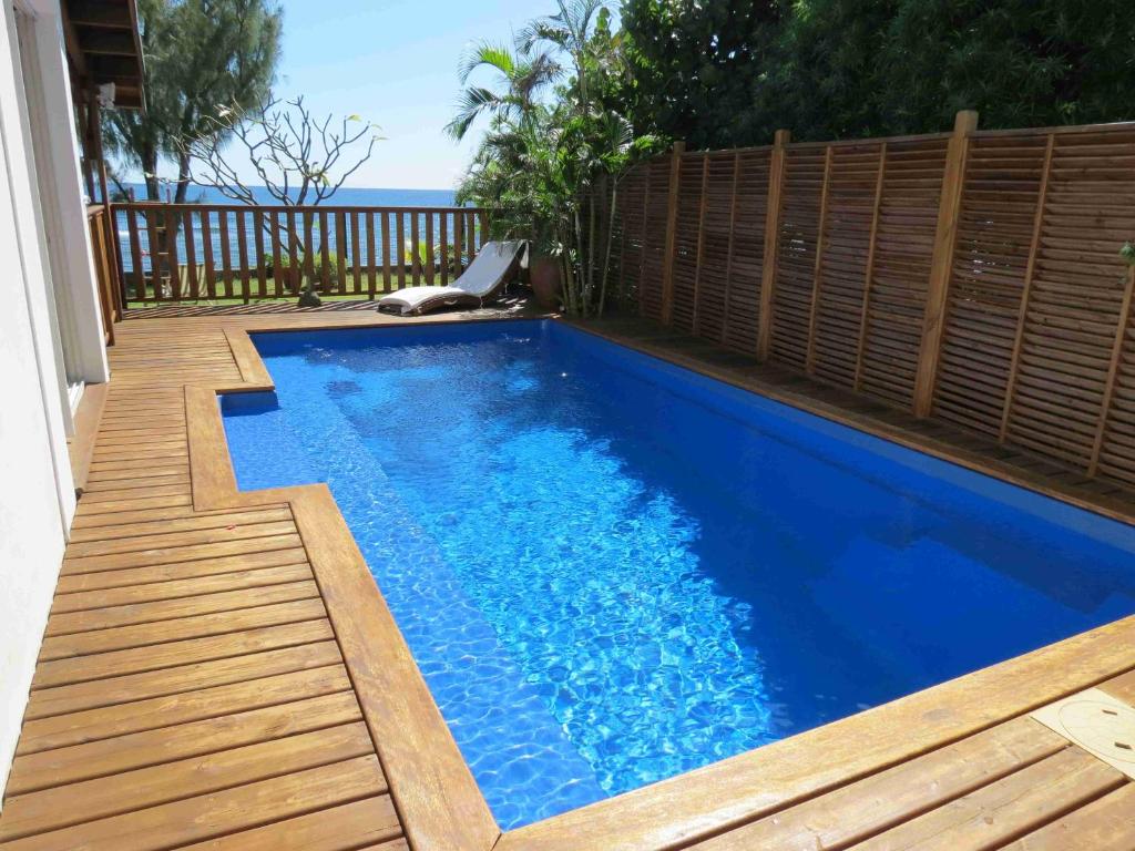 uma pequena piscina azul com um deque de madeira em Villa Bourbon avec piscine sur la plage em Saint-Gilles-les-Bains