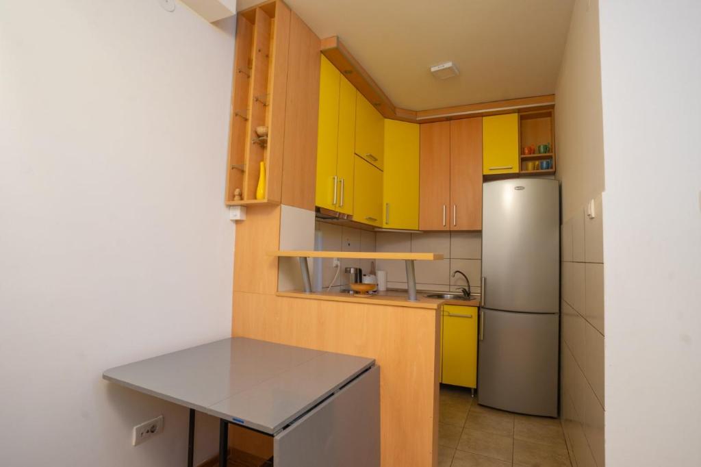 Una cocina con gabinetes amarillos y un refrigerador. en Lorono Kosta, en Belgrado