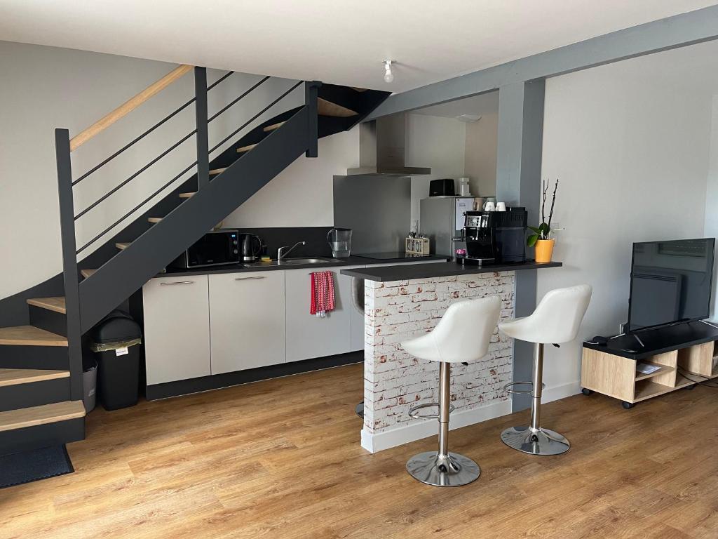 una cocina con escalera, armarios blancos y sillas en Maison de 2 chambres proche A11 Ancenis, Logis du Château Rouge, en Mésanger
