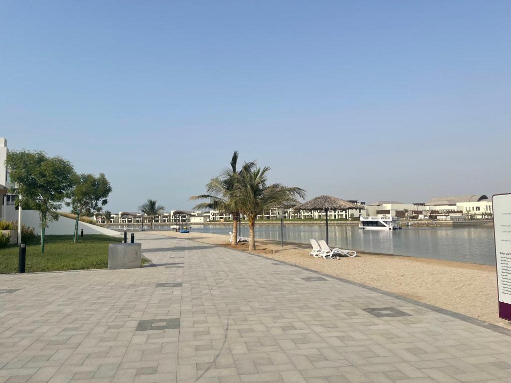 a sidewalk next to a body of water with palm trees at Villa Elena Hayat Island Marbella in Ras al Khaimah