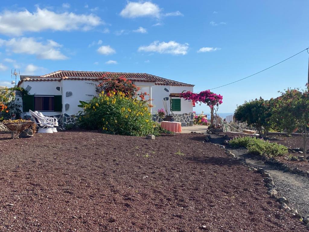 une maison blanche avec des fleurs devant elle dans l'établissement Finca Arcoíris Tenerife VV, à Guía de Isora