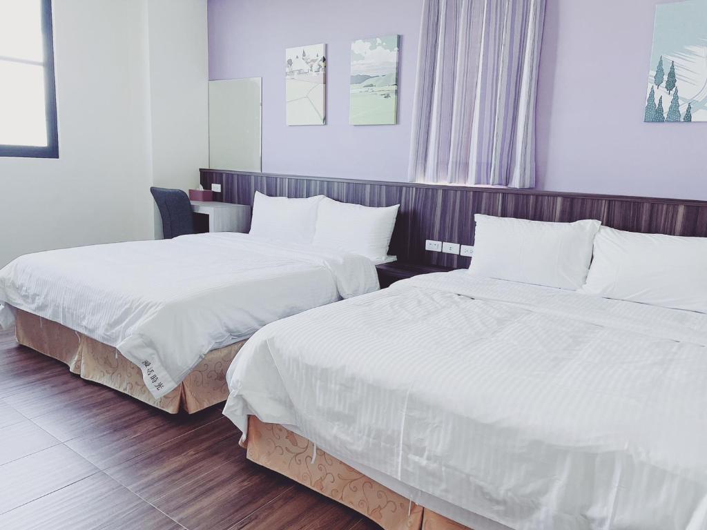 2 camas en una habitación de hotel con sábanas blancas en 漫活時光民宿 Leisure Living en Baisha
