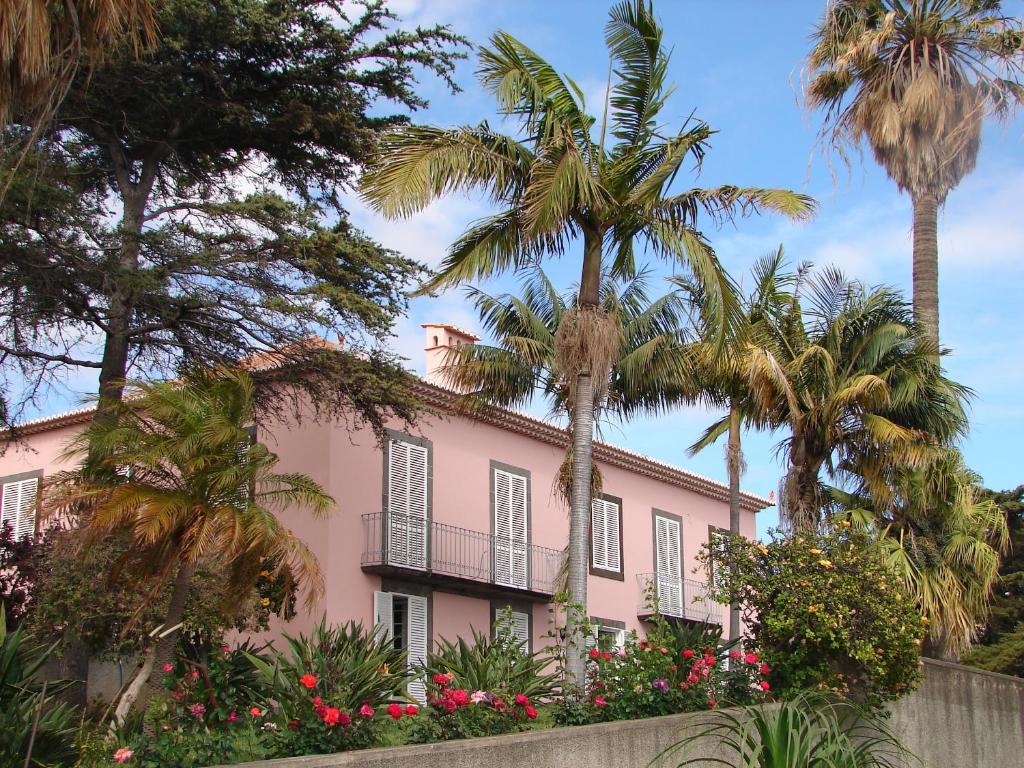 une maison rose avec des palmiers et des fleurs dans l'établissement Quinta do Bom Sucesso, à Funchal