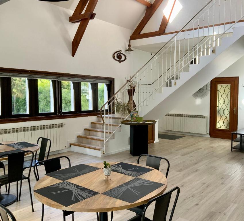 een kamer met tafels, stoelen en trappen bij Villa Manoca in Boisemont