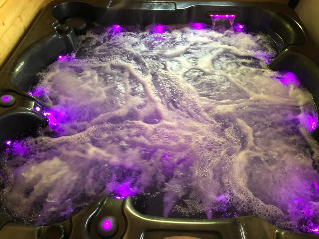 un pot d'eau bouillante avec des lumières violettes dans l'établissement Une Pause Douceur - Suite All in Wood, à Eyguières