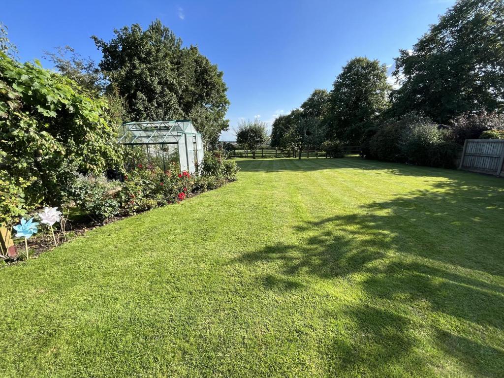 un patio con césped verde y invernadero en Stunning 5 bedroom country home with amazing views, en Leamington Spa