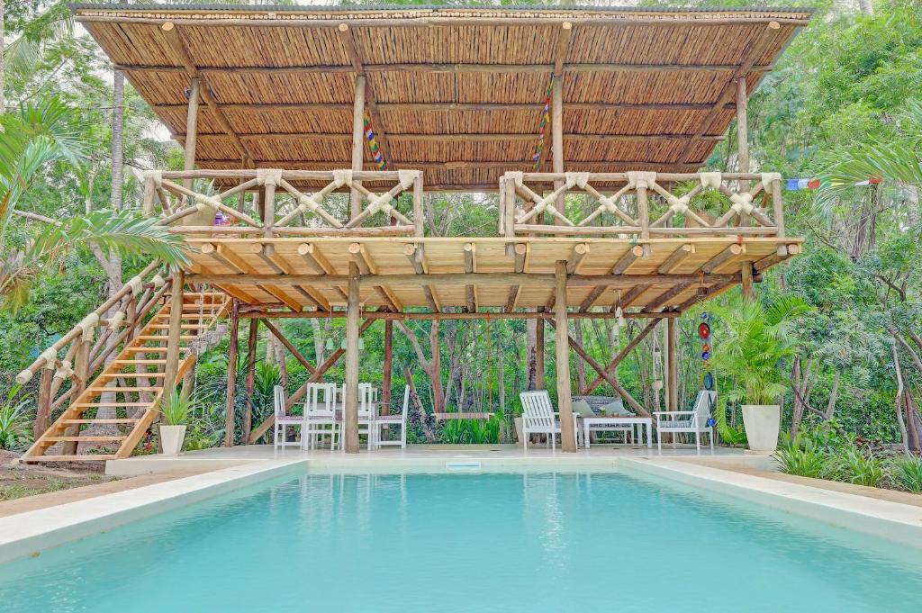 uma pérgola de madeira sobre uma piscina com um deque em Salama House - your peaceful, poolside retreat em Watamu