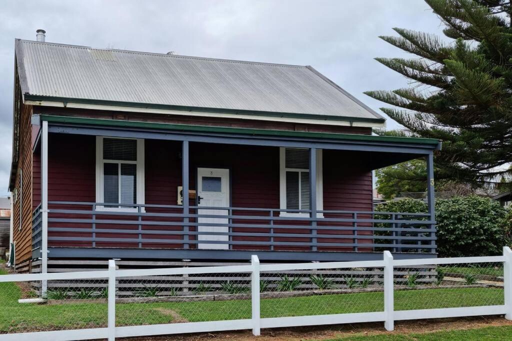 uma casa vermelha com uma cerca branca à frente. em Millhouse on Pine em Pemberton