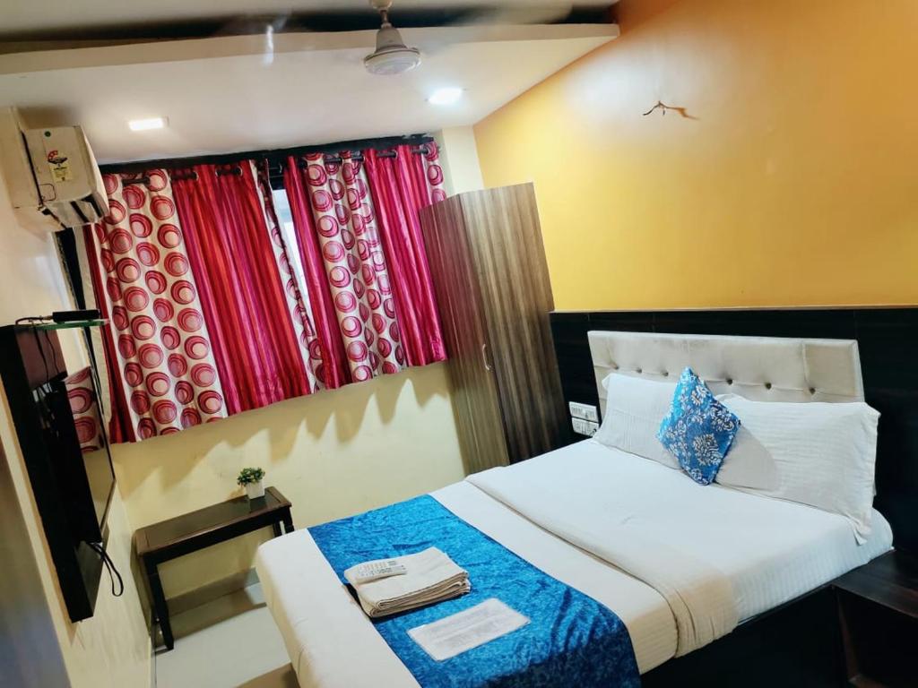 a bedroom with a bed and a window with curtains at Hotel Golden Galaxy - Santacruz East in Mumbai