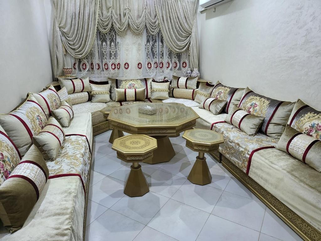 un soggiorno con un lungo divano e un tavolo di Appartement near airport ouled tayeb a Al Hachlaf