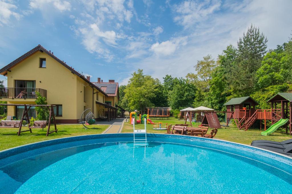 - une grande piscine dans une cour avec une aire de jeux dans l'établissement Apartamenty Gajówka- rowery, plac zabaw, sauna, jacuzzi, à Stegna