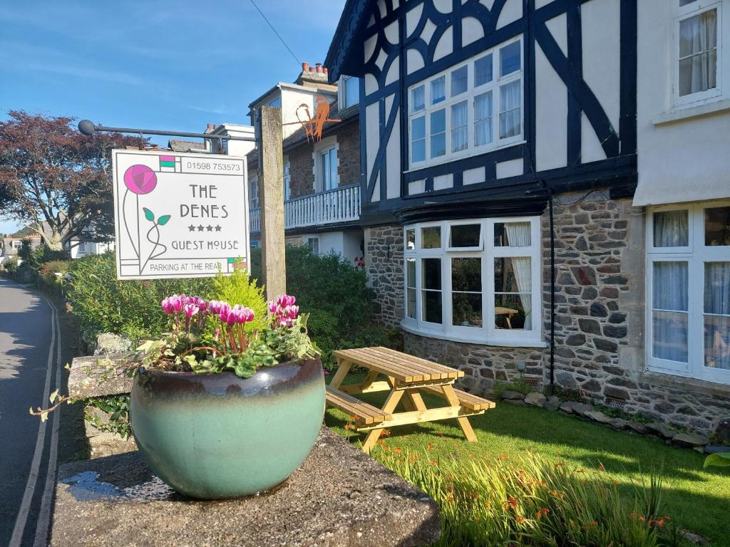 um cartaz e um vaso de flores em frente a um edifício em The Denes em Lynton