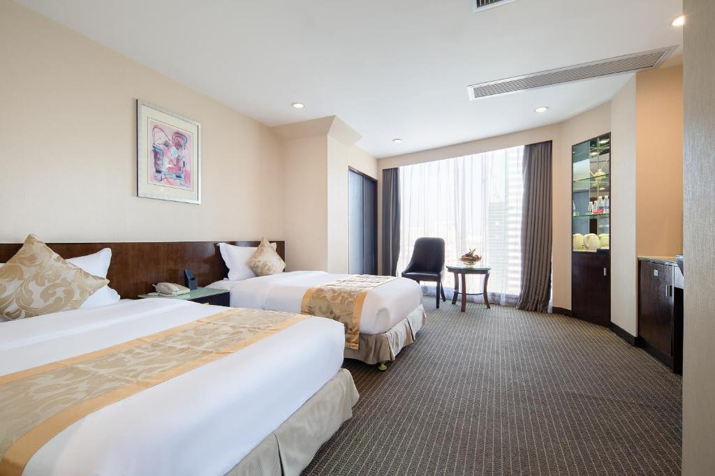 a hotel room with two beds and a desk at Yihe Hotel Ouzhuang in Guangzhou