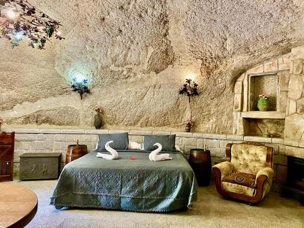 un dormitorio con dos cisnes en una cama y una silla en Cueva romántica - Jacuzzi en La Cabrera