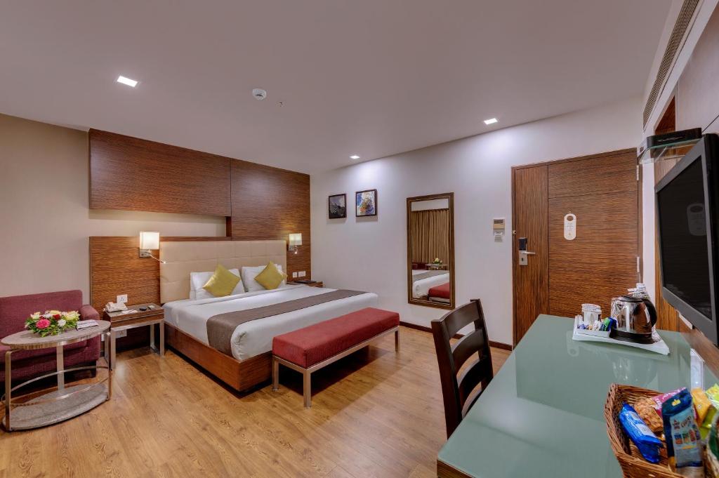 アーメダバードにあるHotel Suba Star Ahmedabadのベッドとテーブルが備わるホテルルームです。