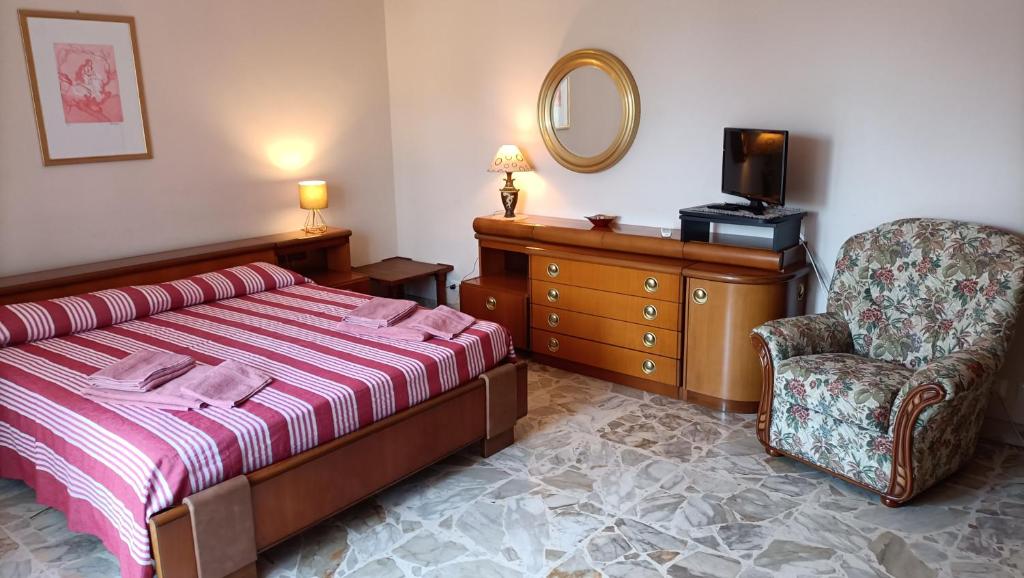 a bedroom with a bed and a chair and a mirror at Magic Etna and glamorous blue sea in Riposto