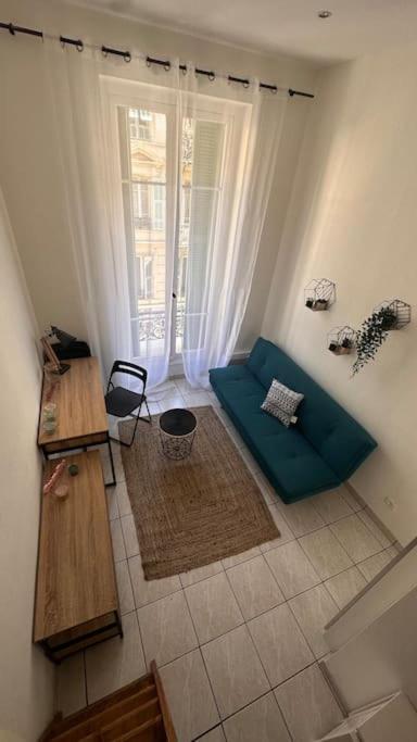 un salon avec un canapé vert et une fenêtre dans l'établissement Charmant studio Jean Médecin, à Nice