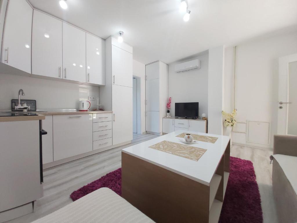 a kitchen with white cabinets and a table in a room at Apartman Kasic in Konjic