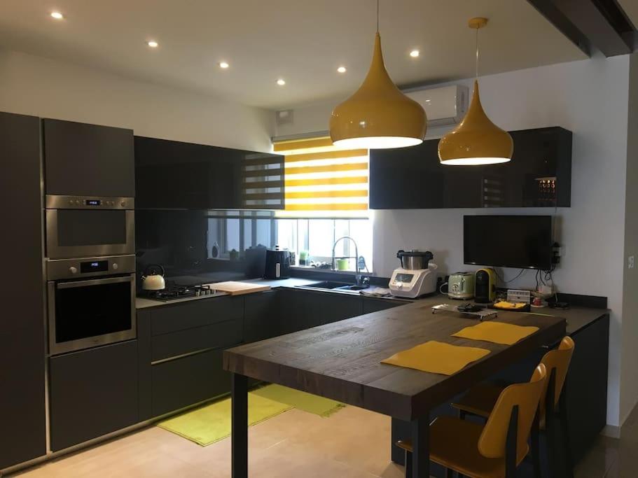 uma cozinha com armários pretos e uma mesa de madeira em Champagne Supernova Penthouse em Santa Vennera