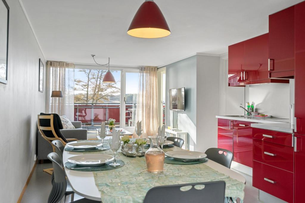 una cucina e una sala da pranzo con tavolo e armadi rossi di Langeby Camping a Sandefjord