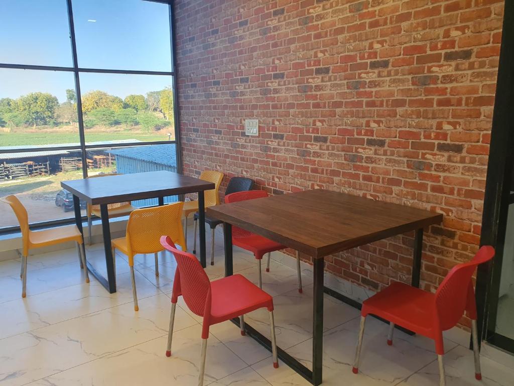 two tables and chairs in a room with a brick wall at Hotel holiday residency in Sāgwāra