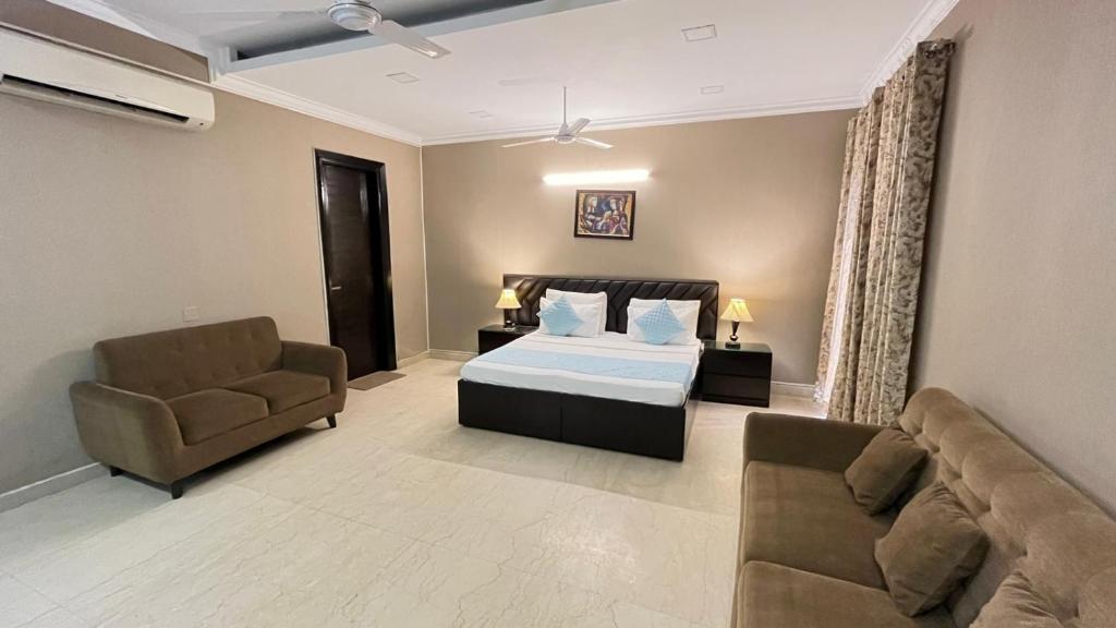 a bedroom with a bed and two chairs and a couch at Abode Residency Safdarjung Enclave Near U S Embassy Delhi in New Delhi