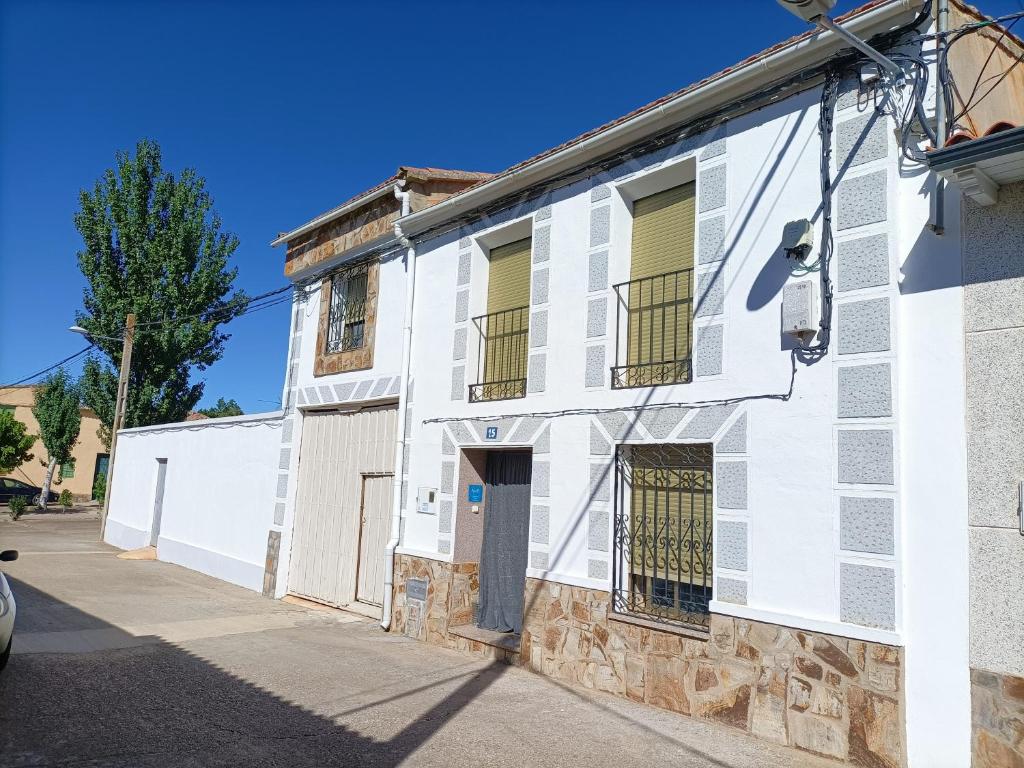 a white building with green shutters on a street at LA VILLA in Villarrín de Campos