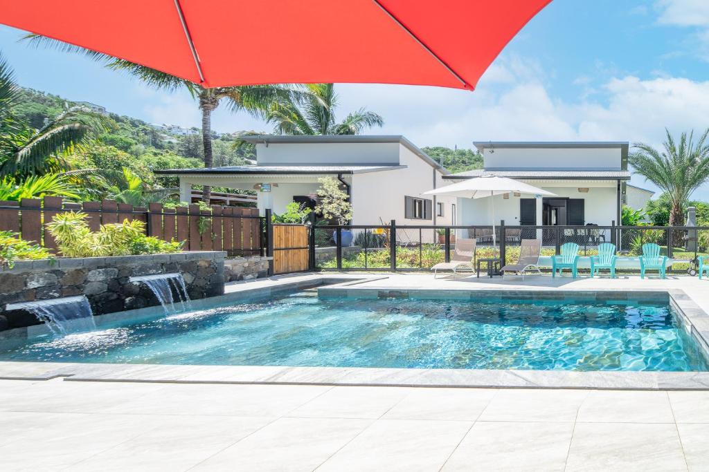 a house with a swimming pool and a red umbrella at Ô Ruisseau Lodge dattier in Saint-Louis