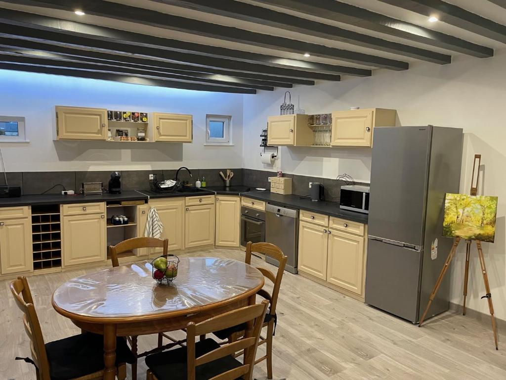 une cuisine avec une table et un réfrigérateur dans l'établissement Gîte La Baz en centre-ville d'un village du Perche - La Bazoche-Gouet, à La Bazoche-Gouet